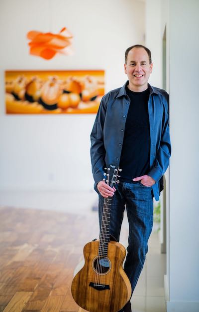 Y. Dan Rubinstein standing with guitar